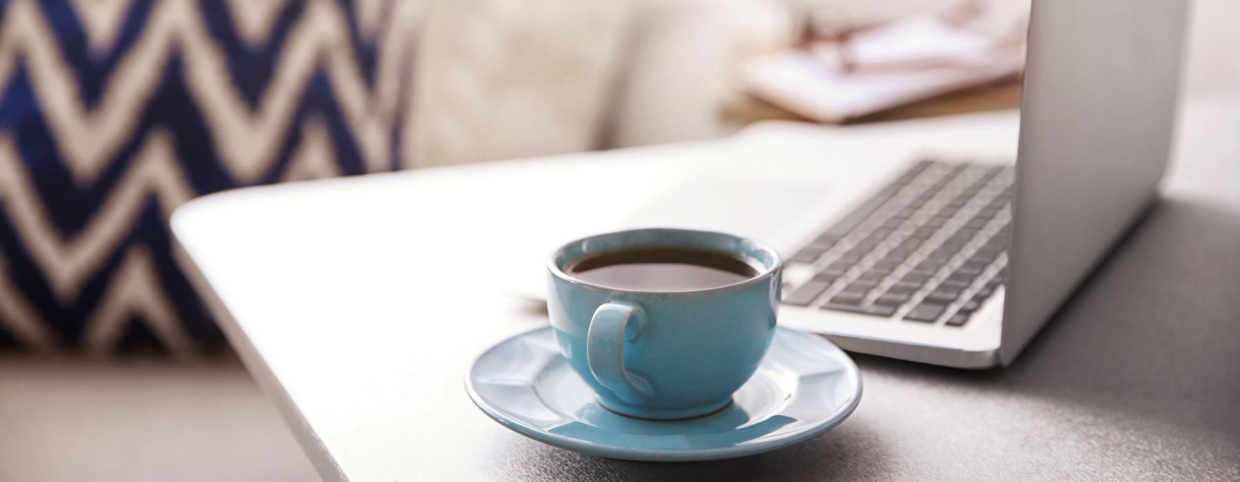 a cup of coffee next to a laptop